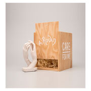 Miniature sculpture replica of two intertwined hands with a wooden packaging crate