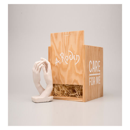 Miniature sculpture replica of two intertwined hands with a wooden packaging crate
