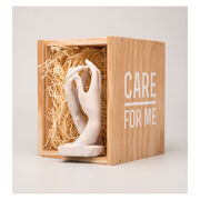 Miniature sculpture replica of two intertwined hands with a wooden packaging crate