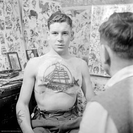 Nigel Henderson: An unidentified man in a tattoo parlour