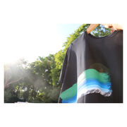 Black t-shirt with blue, green and white stroke against a black t-shirt, against a leafy backdrop