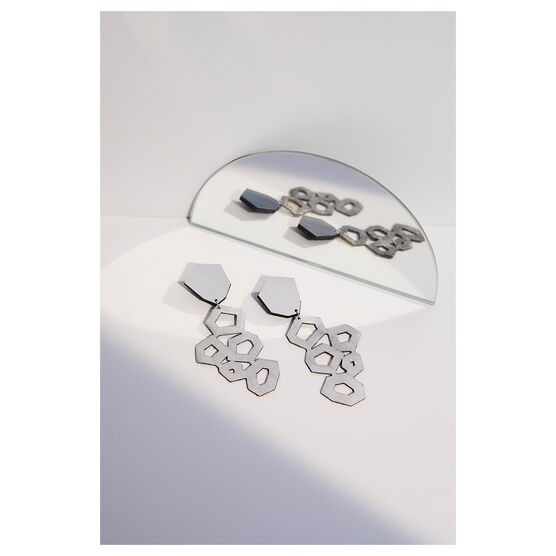 silver leather earrings, laying flat next to a mirror
