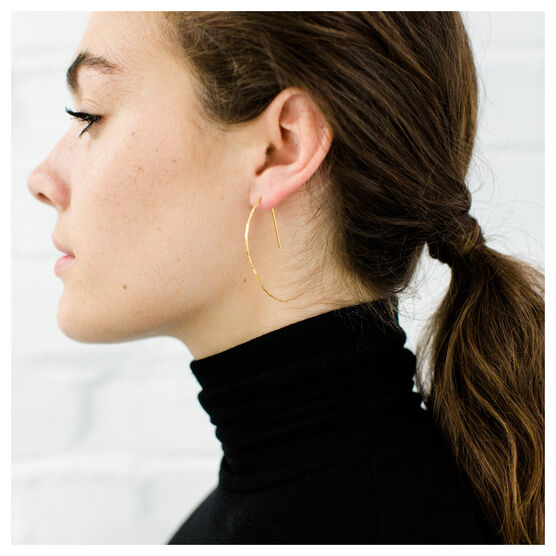 Gold hammered metal earrings in a crescent shape on model