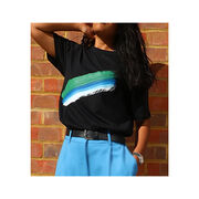 Model standing against a brick wall wearing black t-shirt with green, blue and white stroke